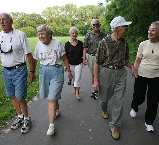 Six older adults walking in a group on a paved road